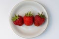 Three strawberries on a white plate. Top view Royalty Free Stock Photo