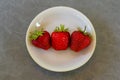 Three strawberries on a white plate. Top view Royalty Free Stock Photo