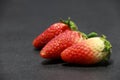 Three Strawberry on the black floor. it is a sweet soft red fruit with a seed studded surface.