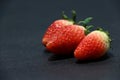 Three Strawberry on the black floor. it is a sweet soft red fruit.