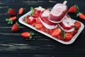 Three strawberry vanilla ice cream popsicles on ice cubes and strawberry slices on the black wooden background. Royalty Free Stock Photo