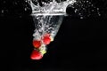 Three strawberrys splashing into water