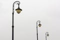 Three street lamps on cloudy sky background