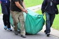 three strong men are dragging a huge green bag with an inflatable trampoline. Events for the City Day