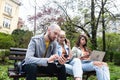 Three students on a bench in the park study talking typing on laptop notebook and writing. Education concept. Young colleagues Royalty Free Stock Photo