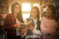 Three students girls reading book together in library. Royalty Free Stock Photo