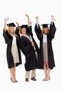 Three students in graduate robe raising their arms Royalty Free Stock Photo