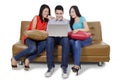 Three students and laptop on the couch Royalty Free Stock Photo