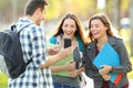 Three students sharing phone content in a park