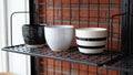 Three stylish ceramic pots displayed on a black metal shelf against a brick wall Royalty Free Stock Photo