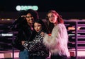 Three stylish girls standing on a street at night