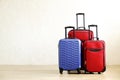 Three suitcases of different size, big & small, red textile and blue hard shell luggage with extended telescopic handle. Family tr