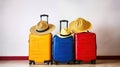 Three suitcases, red textile and blue hard shell luggage, extended telescopic handle, straw hat, yellow beach bag, white textured Royalty Free Stock Photo
