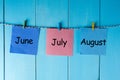 Three summer month - June, July and August - on notes pinned at wooden wall. Summer calendar concept