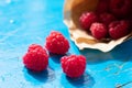 Three sun illuminated backlit red raspberries on rustic blue painted background Royalty Free Stock Photo