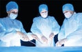 Three surgeons, a man and a woman, perform surgery in the operating room to remove and transplant human organs, resect