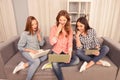 Three surprised pretty girls sitting on the couch with laptop Royalty Free Stock Photo