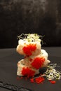 Three sushi rolls with tobiko caviar set on top of each other on a slate board. Royalty Free Stock Photo