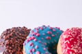 Three sweet, colorful doughnuts in a row close-up on a light background. Free space for copying Royalty Free Stock Photo