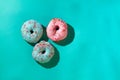 Three sweet donuts pink and blue with multi-colored round sprinkles sugar on a blue background