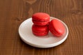 Three Sweet strawberry red macarons on a dark wood background. Tasty colourful macaroons.