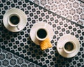 Three espresso coffee cups and saucers on pattern table cloth Royalty Free Stock Photo
