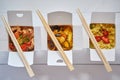 Three take away paper boxes filled with asian food placed in row on white