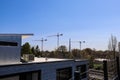 Three tall tower cranes surrounded by bare winter trees and lush green trees with clear blue sky in Atlanta