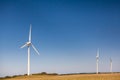 Three tall wind turbines under blue sky.