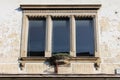 Three tall windows with decorative concrete frame and small flower pot in front on cracked dilapidated house wall Royalty Free Stock Photo