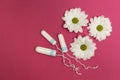 Three tampons on a pink background with white flowers