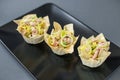 Three tartlets with tuna and onions on a black plate, buffet appetizer for buffets
