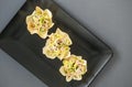 Three tartlets with tuna and onions on a black plate, buffet appetizer for buffets. Beautifully decorated catering