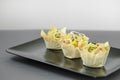 Three tartlets with tuna and onions on a black plate, buffet appetizer for buffets