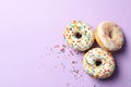 Three tasty donuts on violet background, top view