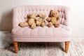 Three teddy bears sitting on pink sofa.