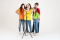 Three teen girls and a boy smiling and shoots a video. Selfies. The phone is mounted on a tripod and the ring lamp shines