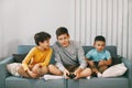 Three of the teen`s best happy friends are playing a video game at home. Three brothers play a video game, sitting on the couch, Royalty Free Stock Photo