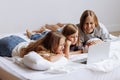 Three teenage girls are lying on the bed with a laptop. Royalty Free Stock Photo