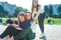 Three teenage girls play and ride on skateboard, in summer in city, rest on break after school and college. Casual warm Royalty Free Stock Photo