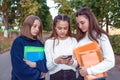 Three teenage girls schoolgirls 12-14 years old, summer city, hand smartphone, online Internet, social networks Royalty Free Stock Photo