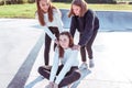 Three teenage girls of schoolgirls 11-14 years old, in summer in city, ride skateboard, happy smiling, having fun Royalty Free Stock Photo