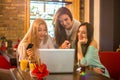 Three teenage girls shopping online together in a cafe. Royalty Free Stock Photo