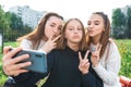 Three teenage girls. They take pictures themselves on phone, happy smiles play and fool around. Online application on