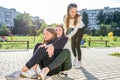 Three teenage girls of 12-14 years old, in summer in city, ride a skateboard, happy smiling, having fun and rejoicing Royalty Free Stock Photo