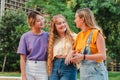 Three teenage gossip girls talking together outside. Group of multiracial female friends chatting and having