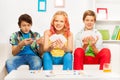 Three teenagers playing table game on white sofa