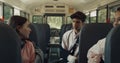 Three teenagers sitting school bus talking alone. Smiling girl taking seat. Royalty Free Stock Photo