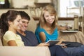 Three Teenagers Sitting On Sofa At Home Using Mobile Phone, Tablet Computer And Laptop Royalty Free Stock Photo