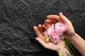 Three tender peonies in the hands of a tender girl. Black rumpled background